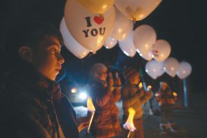 Children carry balloons before releasing them towards Damascus city, in Jobar